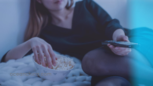 woman with popcorn and tv remote on cozy blanket