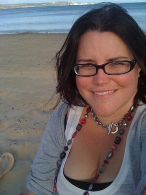 me smiling at the camera at the beach, the ocean behind me